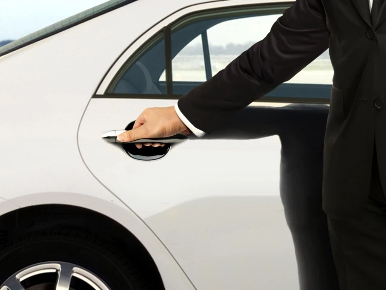 Elegancko ubrana osoba trzymająca ręką klamkę pojazdu